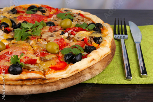 Delicious pizza close-up on wooden table on room background