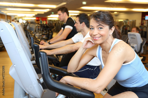 Two man and a woman on exercise bike smiling