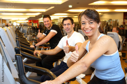 Two man and a woman on exercise bike showing thumbs up