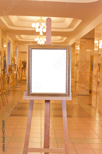 wooden picture frame on easel in art gallery