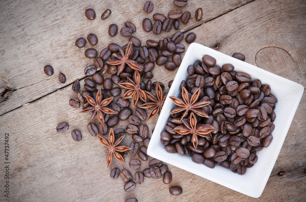 Fototapeta Coffee beans and star anise in a white bowl on wooden background