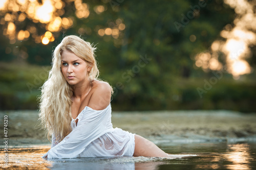 Sexy blonde woman play in lingerie in a river water.