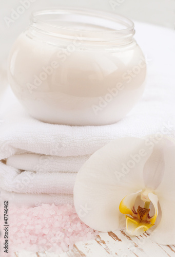 container of cosmetic moisturizing cream with white orchids and