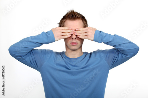 Young man covering his eyes