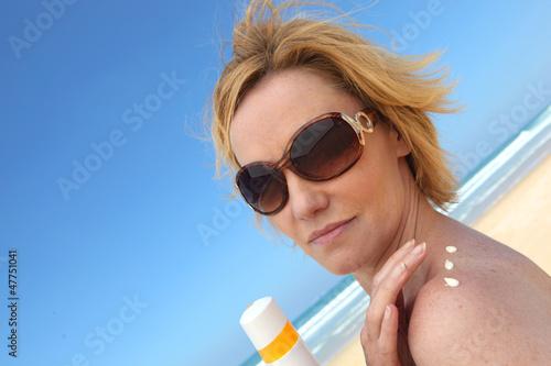 Woman at beach applying sun cream