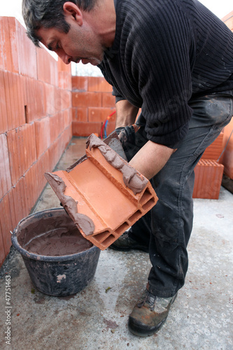 Mason spreading cement on brick photo