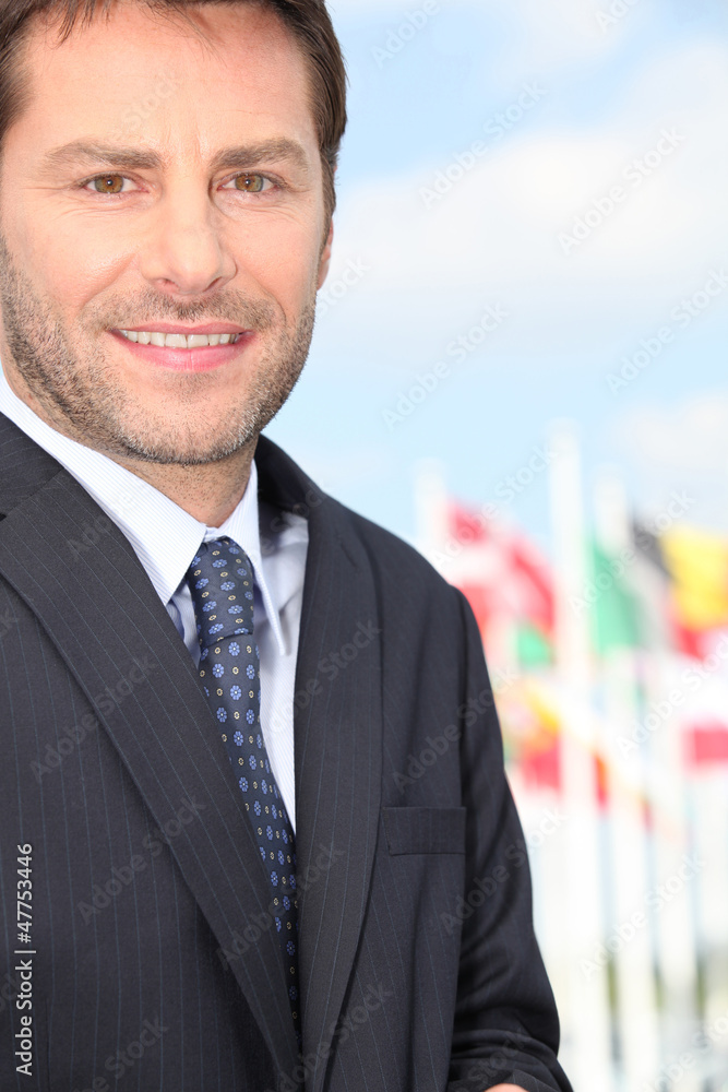 Businessman standing in front of international flags Businessman standing in front of international flags