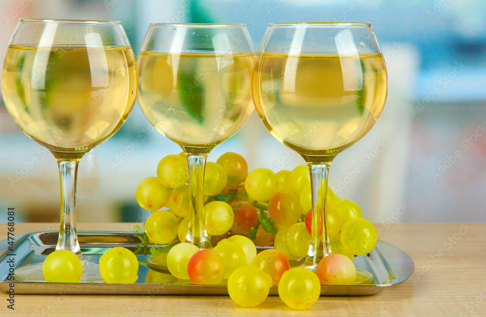 White wine in glass on salver on room background White wine in glass on salver on room background