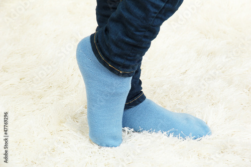 Female legs in colorful socks on  white carpet background
