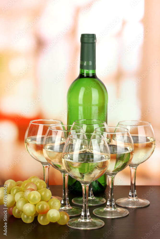 Fototapeta premium White wine in glass and bottle on room background