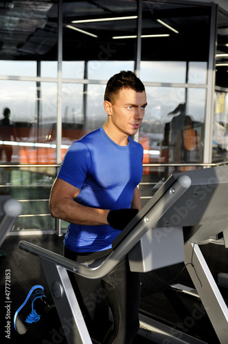 Young man run on treadmill in sunlight
