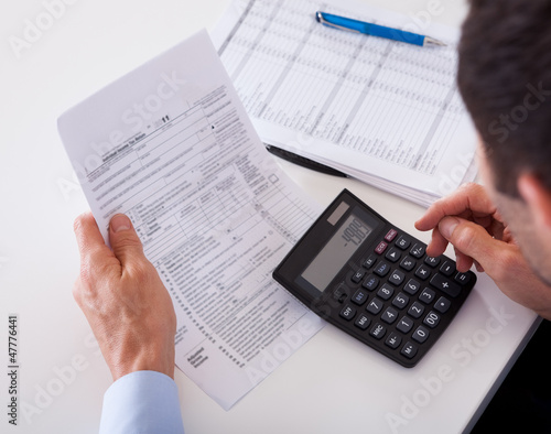 Man checking an invoice on a calculator