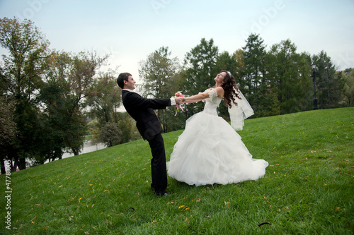 Newly married couple dancing in field