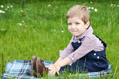 Мальчик сидит в парке на пледе photo