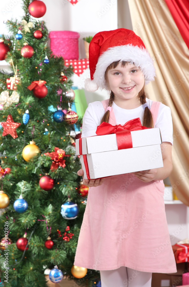 Little girl with Christmas toys in festively decorated room