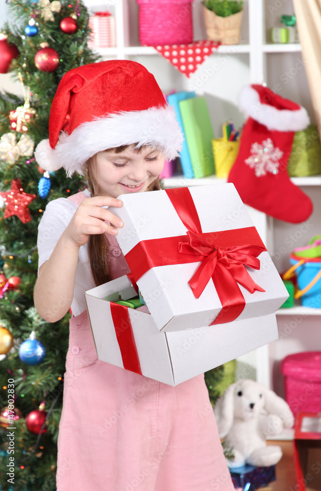 A little girl opens a gift in festively decorated room A little girl opens a gift in festively decorated room