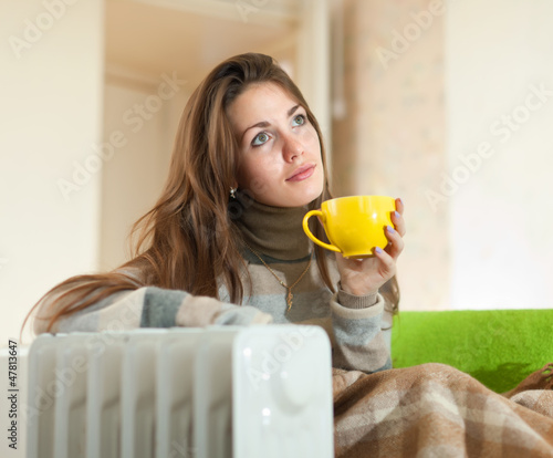 woman near oil heater at home photo