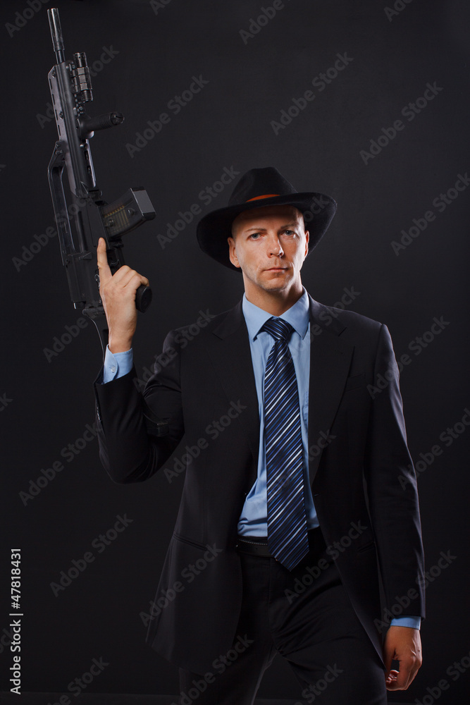 Serious man in a suit holding a rifle