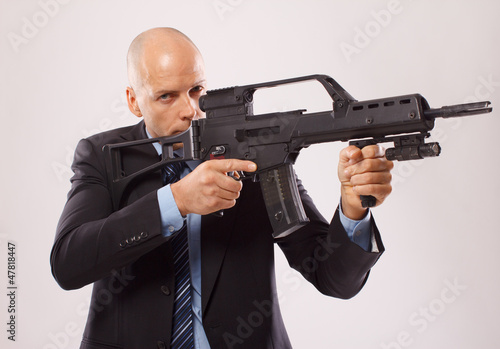 Serious man in a suit holding a rifle