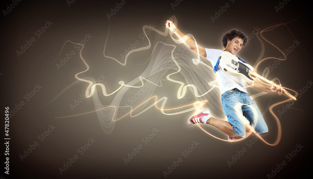 young man playing on electro guitar and jumping