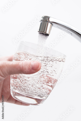 Wasserglas wird am Wasserhahn gefüllt