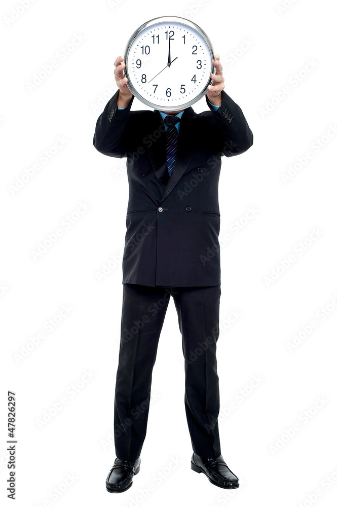 Executive holding up wall clock in front of his face Executive holding up wall clock in front of his face