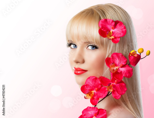 Beautiful blonde young girl with red orchid flowers