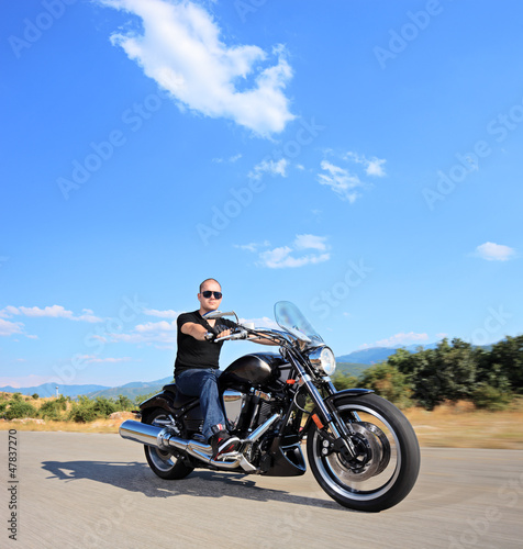 A biker riding a customized motorcycle on an open road