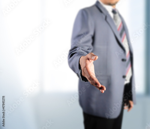 Business man standing for handshake in front of his office