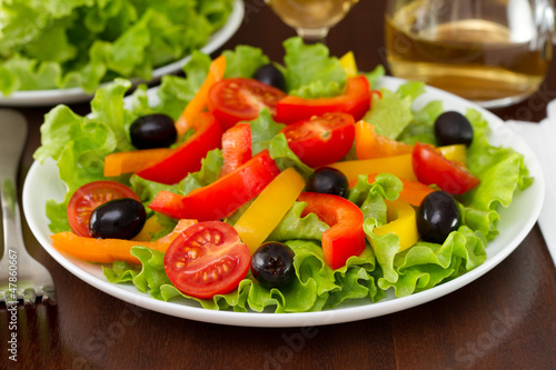 salad with pepper, olives and lettuce on the plate