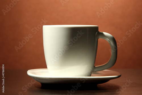 cup of coffee on wooden table, on brown background