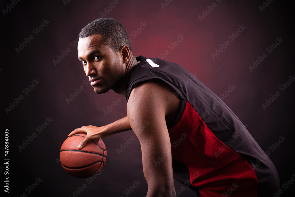Portrait of a young male basketball player against black backgr Portrait of a young male basketball player against black backgr