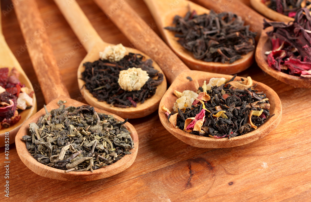 assortment of dry tea in spoons, on wooden background assortment of dry tea in spoons, on wooden background