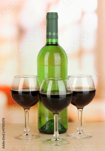 Red wine in glass and bottle on room background