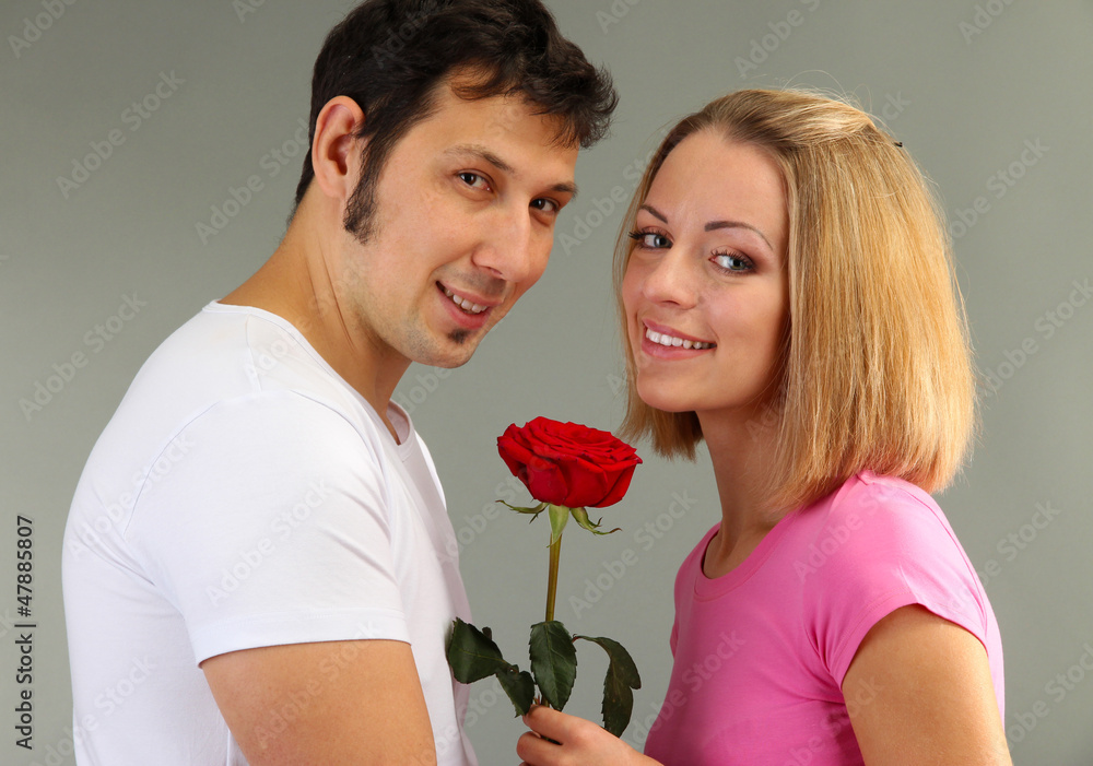 Loving couple with rose on grey background Loving couple with rose on grey background