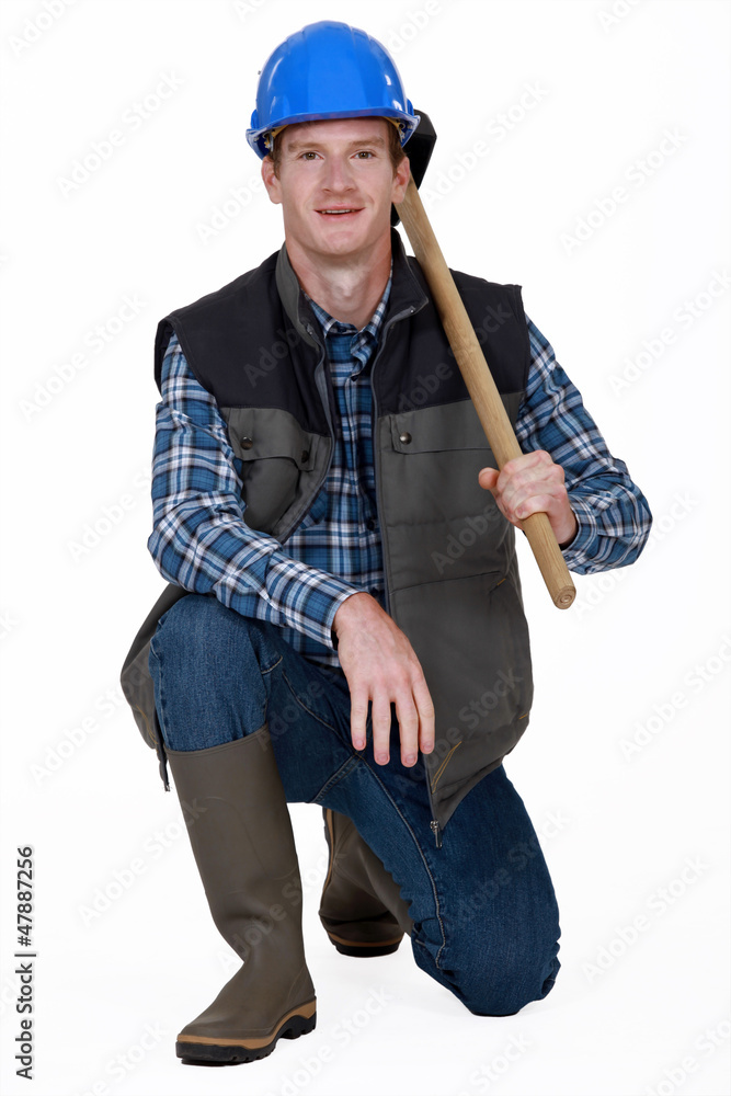 Worker kneeling with sledge-hammer over shoulder Worker kneeling with sledge-hammer over shoulder