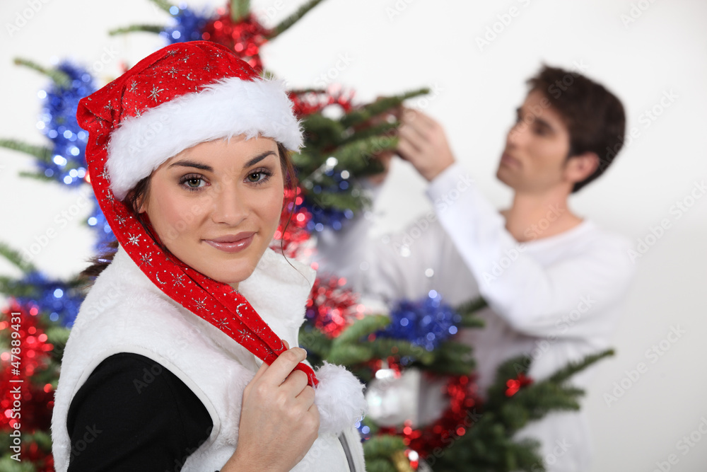 Woman with Christmas cap and man decorating fir