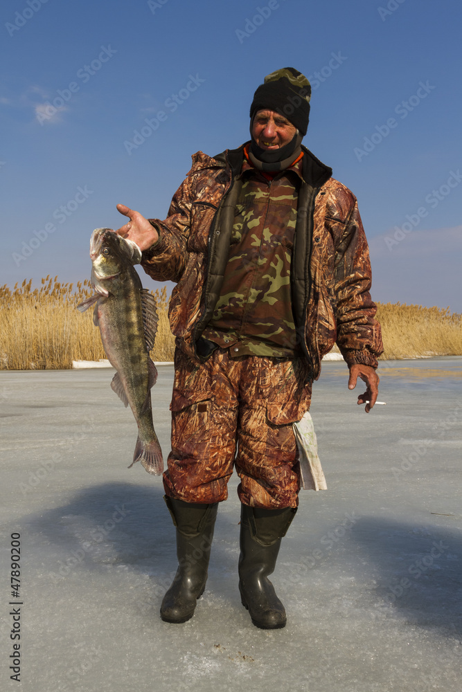 Naklejka premium A man with a catch after ice fishing.