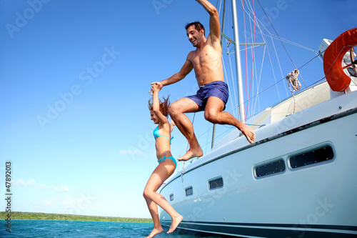 Young couple jumping in water from yacht © goodluz