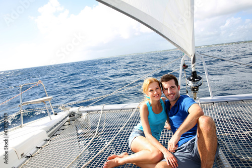 Couple relaxing on catamaran net looking at the sea