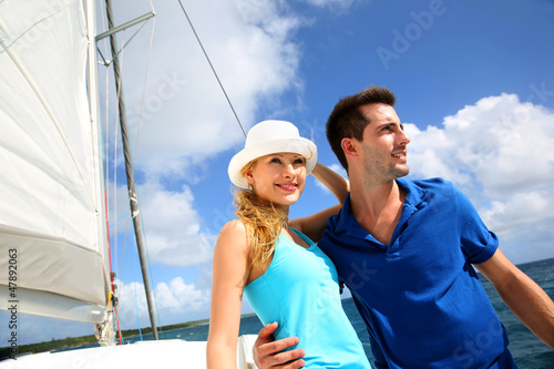 Smiling rich young couple on a sailboat in Caribbean sea