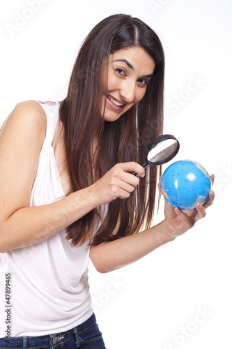 Pretty female in suit holding a globe and using a magnifying gla