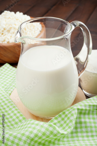 Milk jug, cottage cheese in rustic wooden plate and sour cream