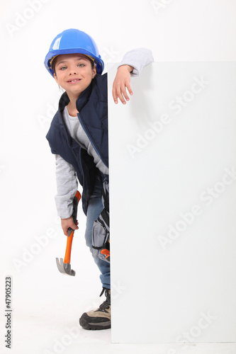 Billede på lærred Little girl dressed as builder stood with poster