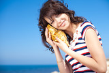 brunette girl posing in the beach, holding shell