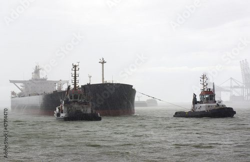 Vessel and tugboats in heavy rain