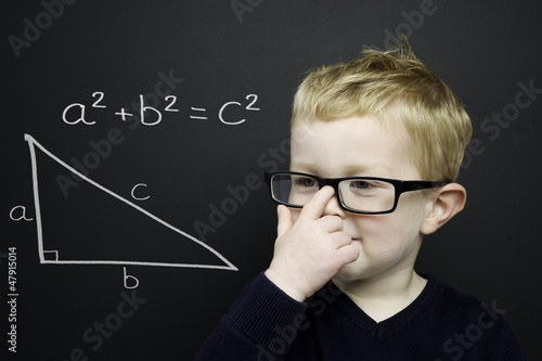 Smart young boy stood infront of a blackboard