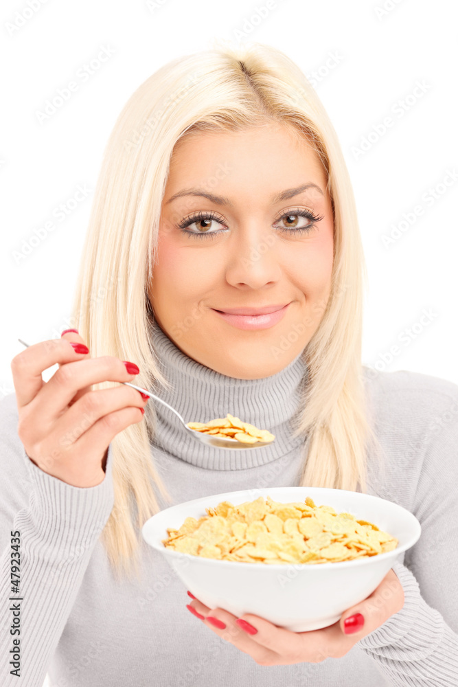 A blond female eating cornflakes at breakfast A blond female eating cornflakes at breakfast