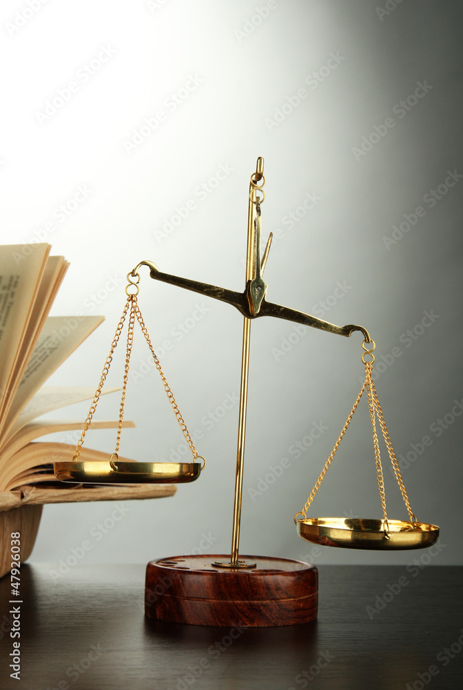 Gold scales of justice and books on grey background Gold scales of justice and books on grey background