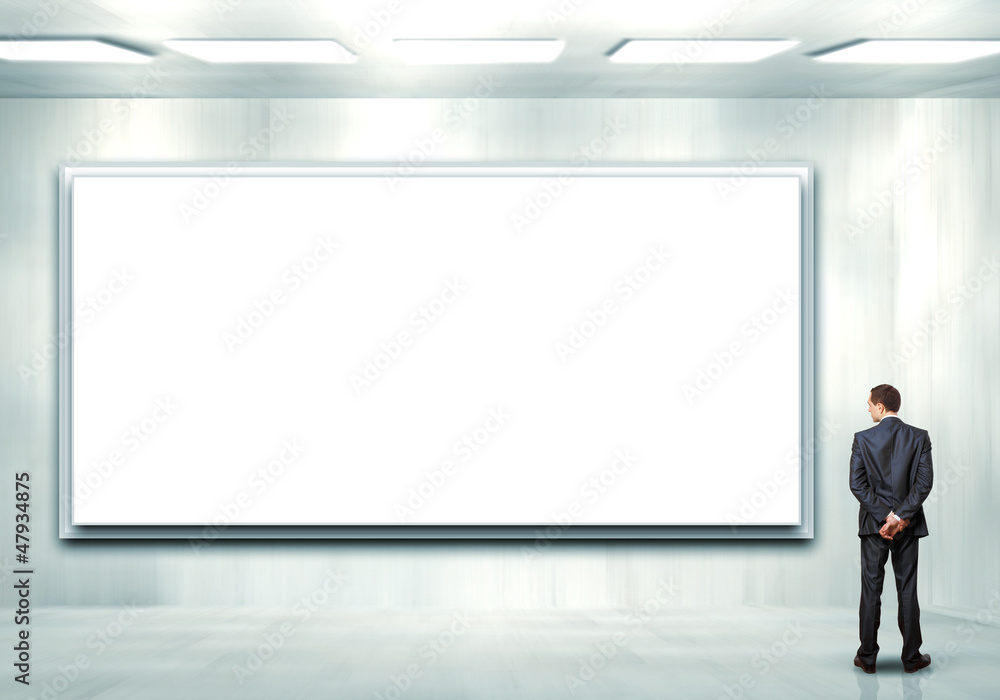 Business person standing near a blank billboard Business person standing near a blank billboard